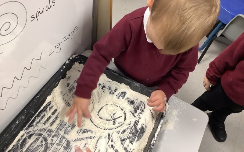 Teaching children to write on sand or flour